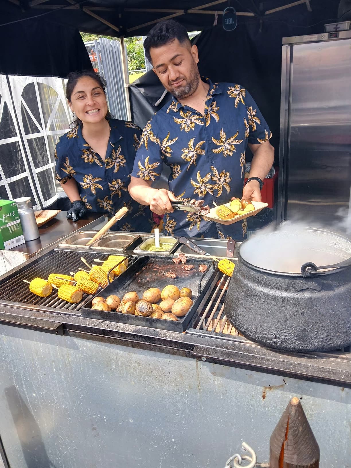 CARACAS Food-Artisten im Palmen-Hemd am Grill — gegrillter Mais, Papas und Beef auf der Parrilla, Teller wird gereicht