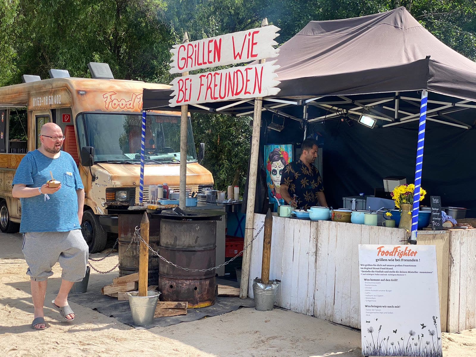 FoodFighter Firmenfeier-Setup: Food Truck, Live-Cooking-Station mit Feuertonne und Grill-Stand nebeneinander
