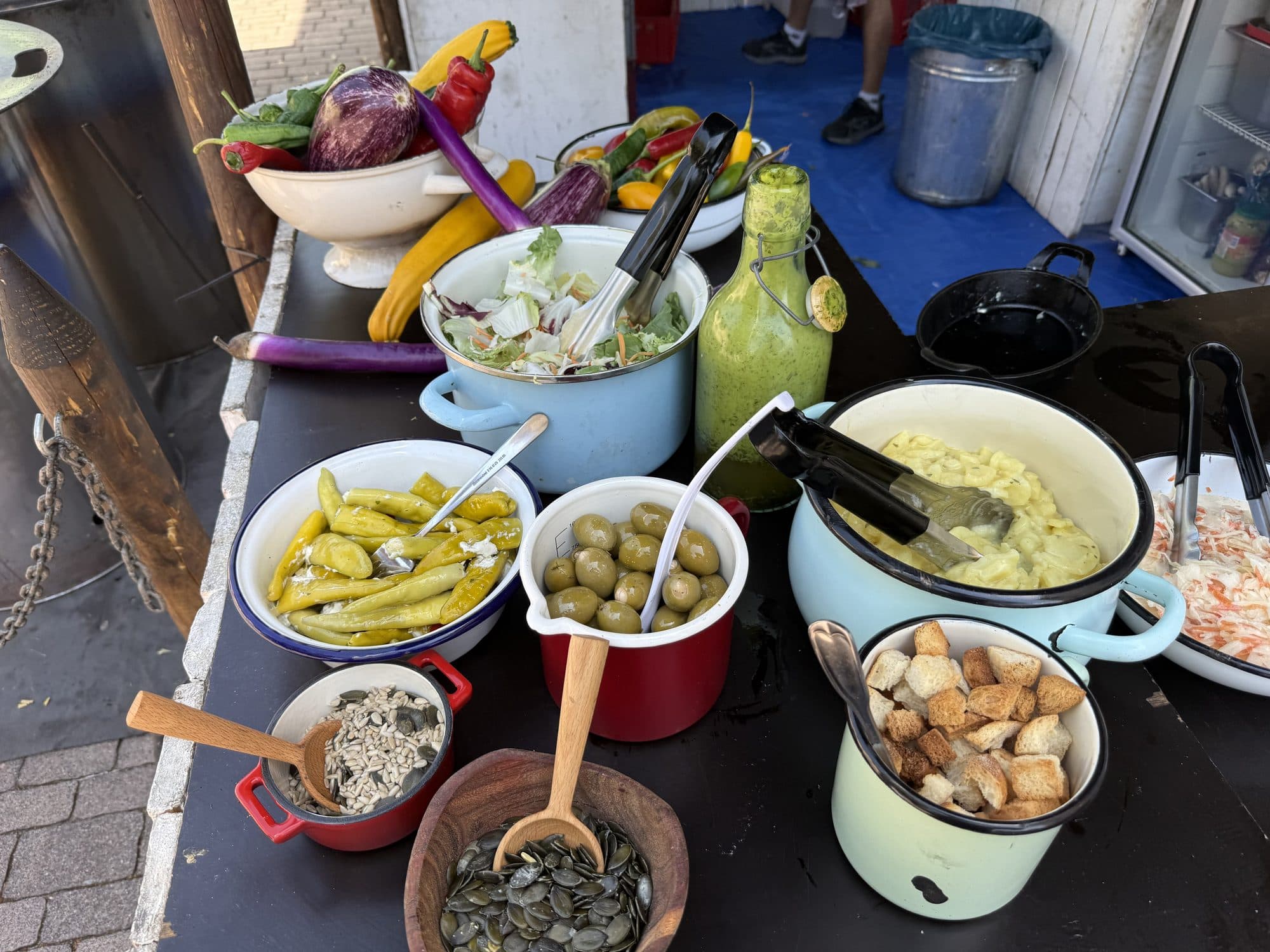 Bunte Salat- und Antipasti-Station mit Oliven, Peperoni und frischen Dressings