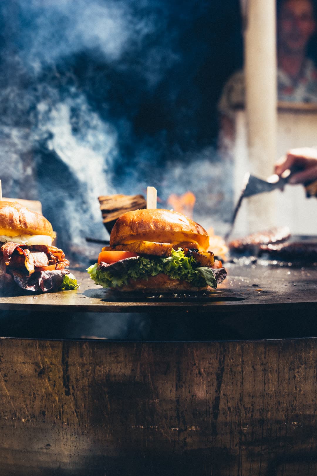 FoodFighter Food-Artist im Hawaiihemd wendet Patty und Ananas auf der Plancha